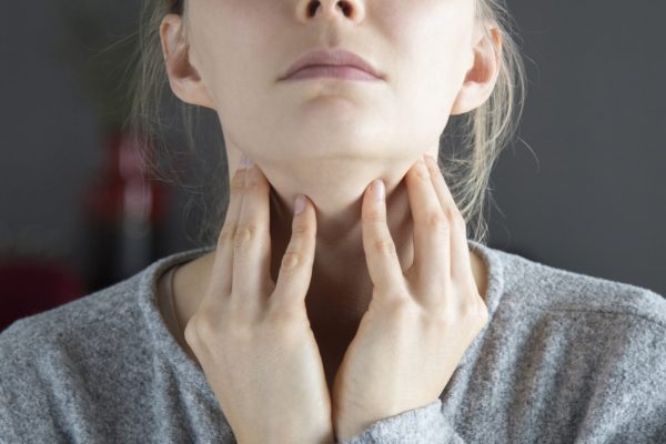 Sick young fair-haired Caucasian woman with closed eyes having sore throat, touching her neck. Illness, pain concept